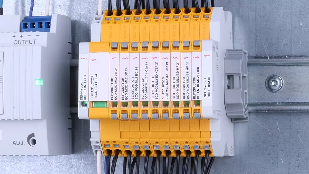 Parafoudre jaune et bleu sur une table, une armoire électrique en arrière-plan.