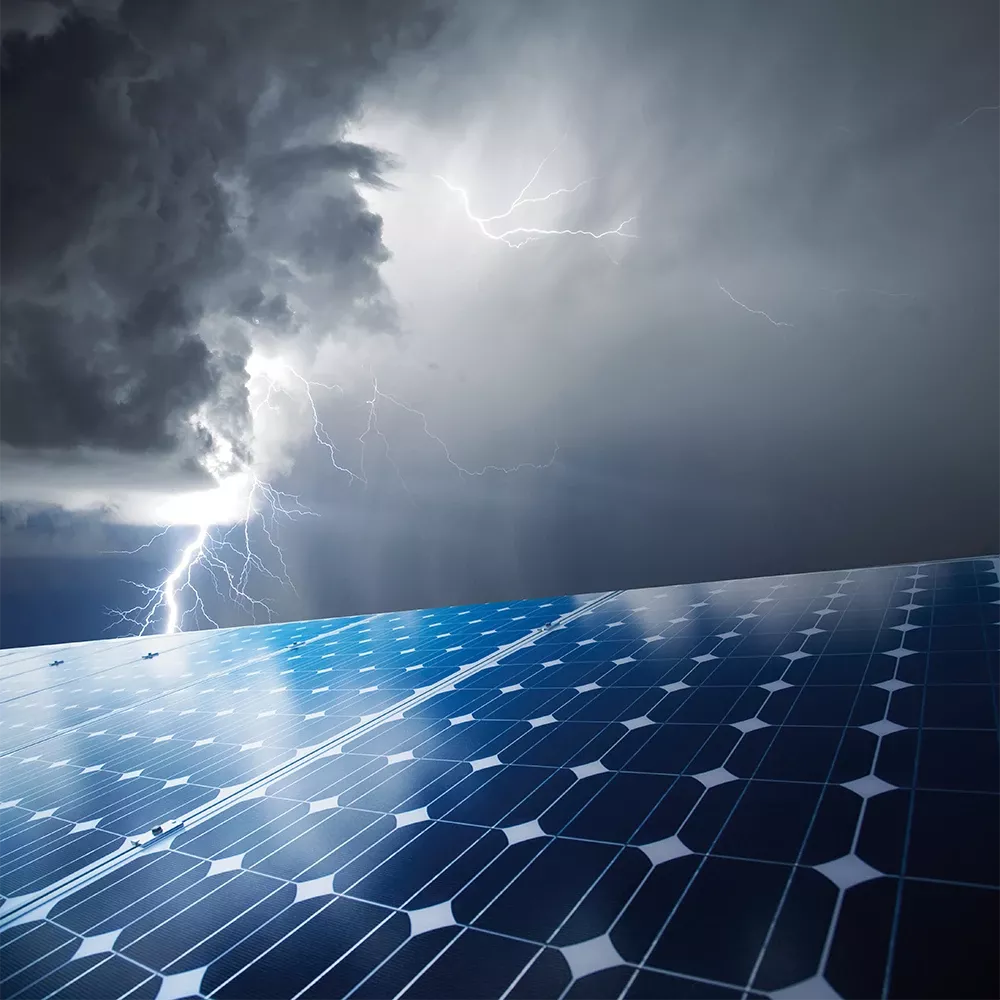 Au premier plan, des panneaux photovoltaïques. En arrière-plan, des nuages d’orage s’accumulent, d’où jaillissent des éclairs.