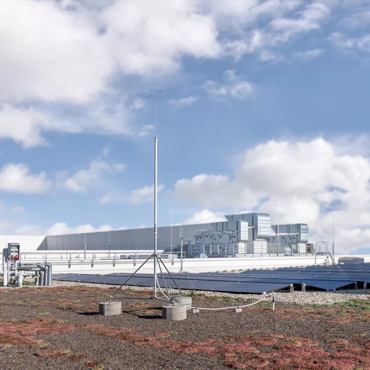 Bâtiment avec un HVI light plus sur le toit plat. En arrière-plan, on peut voir une installation photovoltaïque.