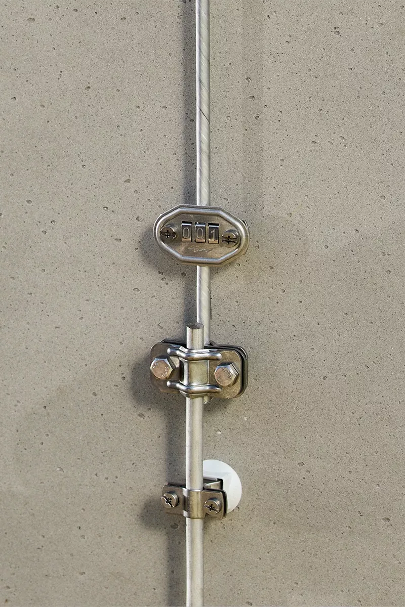 Dérivation composée d’un conducteur rond et de bornes, le tout monté sur un mur en béton.